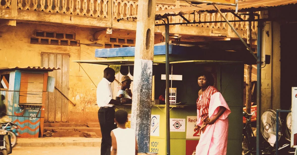 Scène dynamique de marché de rue représentant la vie africaine locale à un stand extérieur.