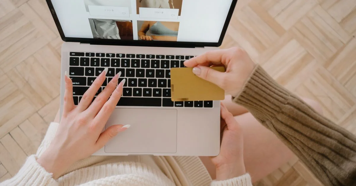 Personne faisant des achats en ligne avec un ordinateur portable et une carte de crédit, mettant en avant la commodité du e-commerce.