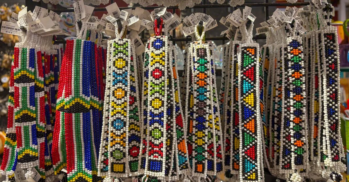 Objets artisanaux africains colorés en perles suspendus dans une boutique de souvenirs, mettant en valeur l'art traditionnel.